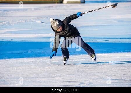 Prag, Tschechische republik - 14. Februar 2021. Kleiner Junge mit Eishockey-Stick in der Hand fallen auf gefrorenen Fluss Stockfoto