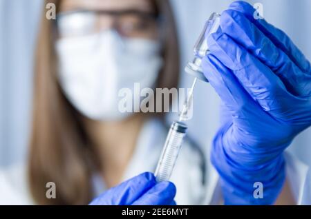 Impfstoff in wissenschaftlichen Händen hält Ärztin Spritze und Flasche mit Impfstoff für Coronavirus Heilung. Konzept der Corona-Virus-Behandlung, Injektion, s Stockfoto