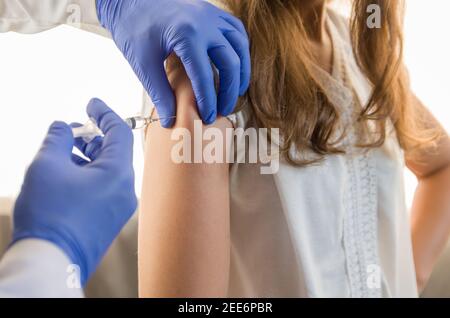 Nahaufnahme Arzt hält Spritze und mit Baumwolle vor der Injektion an den Patienten in medizinische Maske. Covid-19 oder Coronavirus-Impfstoff. Stockfoto