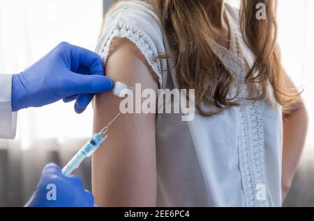 Nahaufnahme Arzt hält Spritze und mit Baumwolle vor der Injektion an den Patienten in medizinische Maske. Covid-19 oder Coronavirus-Impfstoff. Stockfoto