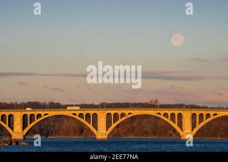 Der Vollmond geht im frühen Morgenlicht über der Key Bridge in Washington, DC, unter. Stockfoto