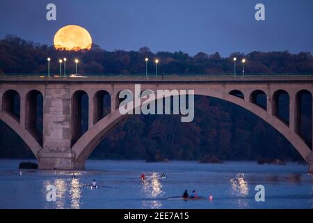 Der Vollmond untergeht über dem Potomac River und der Key Bridge, die Arlington, Virginia und Washington, DC verbindet. Stockfoto