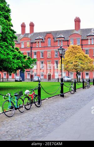 Fahrräder und Grün führen zu den Rubriken am Library Square auf dem Campus-Viereck des Trinity College in Dublin. Die rotgemauerte Rubrik stammt aus dem Jahr 1700 Stockfoto