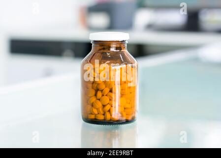 Kleine Pillen in Bernstein Medizin Flasche am Tisch in Apotheke Stockfoto