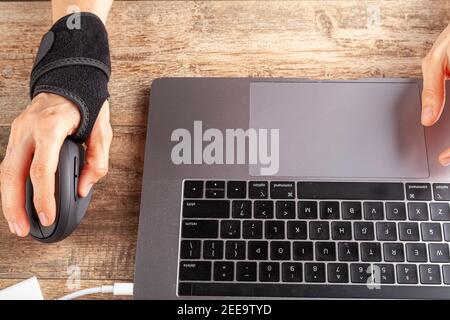 Chronische Verletzungen des Handgelenks bei Menschen mit Computer-Maus kann zu Störungen führen, die Entzündungen und Schmerzen verursachen. Eine Frau, die an der Rezeption arbeitet, benutzt sie Stockfoto