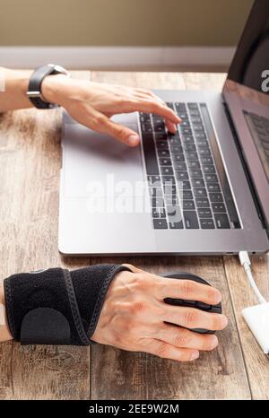 Chronische Verletzungen des Handgelenks bei Menschen mit Computer-Maus kann zu Störungen führen, die Entzündungen und Schmerzen verursachen. Eine Frau, die an der Rezeption arbeitet, benutzt sie Stockfoto