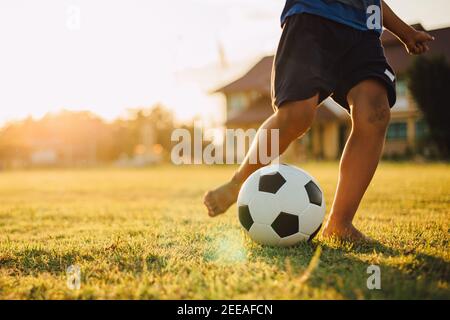 Silhouette Action Sport im Freien einer Gruppe von Kindern Spaß beim Fußball spielen Fußball für die Ausübung in der Gemeinde ländlichen Raum unter der Dämmerung Sonnenuntergang. Stockfoto