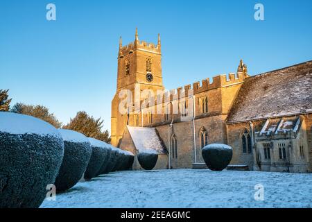 St. Peter und St. Paul Kirche im januar Schnee kurz nach Sonnenaufgang. Long Compton, Warwickshire, England Stockfoto