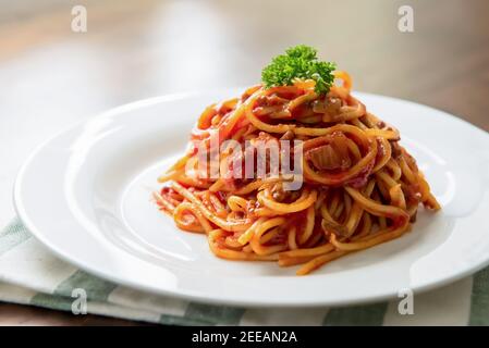 Köstliche italienische Bolognese Fleisch Spaghetti mit Petersilie auf der Oberseite dekoriert In weißer Schale am Tisch Stockfoto