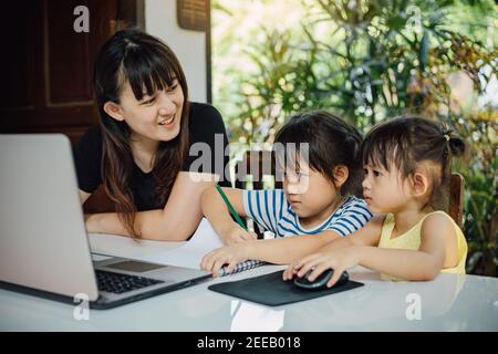 Glückliche Familie von Mutter und Vorschultochter mit Laptop für Fernstudium zu Hause. Mutter lehrt Kinder Hausaufgaben über Online-Klassenzimmer zu tun. Stockfoto