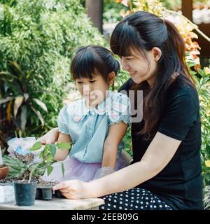 Kleine Kinder spielen und erkunden im Garten mit ihrem Pflanzsprießen. Konzept für umweltfreundliches Gartenbau und nachhaltiges Wohnen. Stockfoto