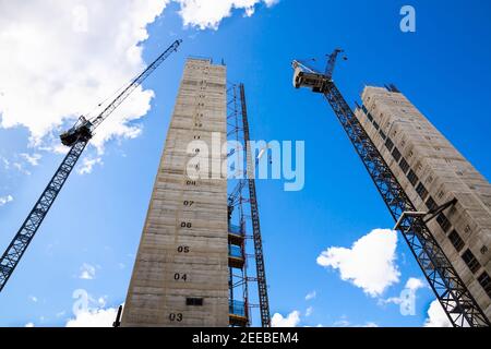 Baustelle mit Kräne und unfertigen Gebäuden auf dem blauen Himmel Hintergrund. Stockfoto