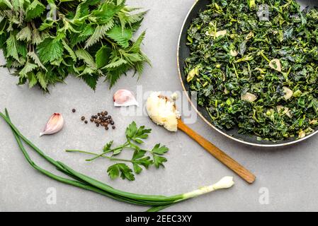 Kochen von grünem Gemüse. Gesundes Essen, vegetarisches Pesto mit grüner Brennnessel und frische Brennnesselblätter gebraten mit Knoblauch und Gewürzen auf Braten pa Stockfoto