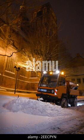 Stralsund, Deutschland. Februar 2021, 16th. Ein Lichtung- und Gitterfahrzeug ist heute früh auf einer verschneiten Straße in der Stadtgrenze unterwegs. Quelle: Stefan Sauer/dpa-Zentralbild/dpa/Alamy Live News Stockfoto