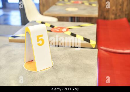 Gelbes schwarzes Klebeband im Café. Soziale Distanz. Getrennte Personen im Restaurant. Auftrag Stockfoto