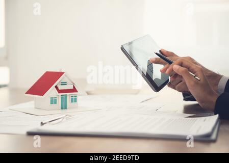 Immobilienmakler mit Client oder Architektenteam Überprüfung ein Gehäusemodell und seine Pläne digital mit Tablet-Computer Stockfoto