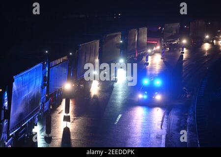 Waidhaus, Deutschland. Februar 2021, 16th. Am frühen Morgen fährt ein Polizeiauto an Fahrzeugen vorbei, die in einem Stau an der deutsch-tschechischen Grenze stecken. In der Nacht vom 14,02.2021 traten die verschärften Einreisebestimmungen Deutschlands an der Grenze zur Tschechischen Republik zum Schutz vor gefährlichen Varianten des Coronavirus in Kraft. Quelle: Armin Weigel/dpa/Alamy Live News Stockfoto