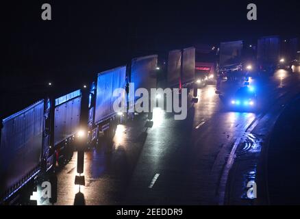 Waidhaus, Deutschland. Februar 2021, 16th. Am frühen Morgen fährt ein Polizeiauto an Fahrzeugen vorbei, die in einem Stau an der deutsch-tschechischen Grenze stecken. In der Nacht vom 14,02.2021 traten die verschärften Einreisebestimmungen Deutschlands an der Grenze zur Tschechischen Republik zum Schutz vor gefährlichen Varianten des Coronavirus in Kraft. Quelle: Armin Weigel/dpa/Alamy Live News Stockfoto