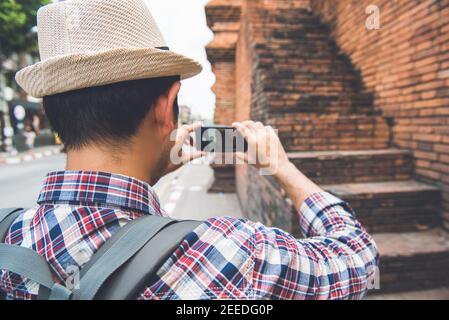 Asiatische männliche Touristen Backpacker fotografieren mit dem Smartphone am Tha Phae Gate, einem der alten berühmten Wahrzeichen der Stadt in Chiang Mai Thailand Stockfoto