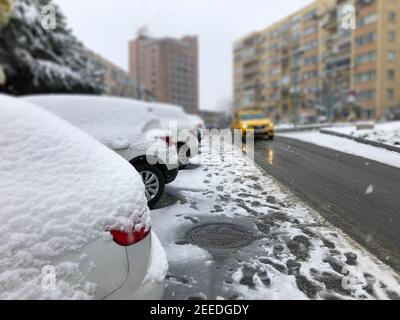 Reihe von Autos unter Schnee geparkt am Straßenrand auf Ein schneereichen Tag im Winter Stockfoto