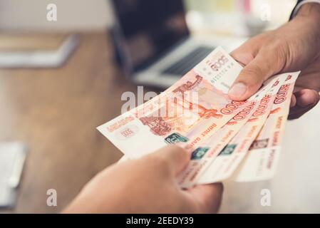 Hand des Geschäftsmannes, der Geld gibt, russische Rubel (RUB) Währung, zu seinem Partner im Büro Stockfoto