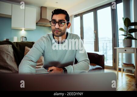 Gemischter Rennbusiness Mann trägt Brille Arbeit von zu Hause tippen Auf Laptop im Wohnzimmer Stockfoto