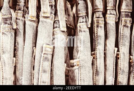 Alte Jeans Größe Reihe im Kleiderschrank oder auf Lager Kleiderbügel. Krawatte Dye Jeans Retro-Stil Foto. Vintage-Kleidung auf Kleiderbügel im Geschäft. Fashion Shop Black Friday Sale. T Stockfoto