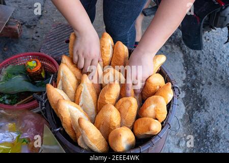 Frisch gebackenes Brot und Frauenhände. Banh Mi bun im Rücken. Hausgemachtes Brotkonzept. Traditionelle Street Food in Vietnam. Vietnamesische Banhmi oder Banmie. Sou Stockfoto