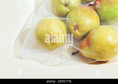 Wiederverwendbare Verpackung von Produkten nach Gewicht. Birnen in einem wiederverwendbaren Beutel Nahaufnahme auf einem rosa Hintergrund Stockfoto