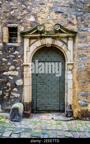 Vorderansicht der Eingangstür eines mittelalterlichen Stadthauses, mit einem gemeißelten Steinrahmen, in einer gepflasterten Straße des historischen Zentrums von Le Mans, Frankreich. Stockfoto