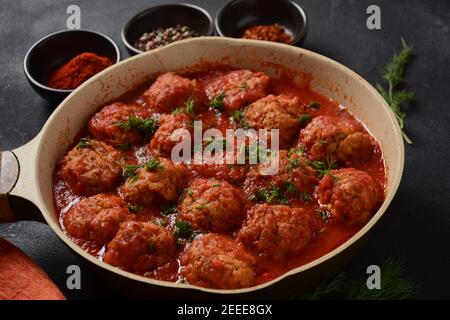 Boulettes de Poisson, gebratene Fischbälle in Tomatensauce in einer weißen Schale auf einem Betontisch mit Zutaten Stockfoto
