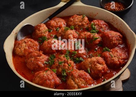 Boulettes de Poisson, gebratene Fischbälle in Tomatensauce in einer weißen Schale auf einem Betontisch mit Zutaten Stockfoto