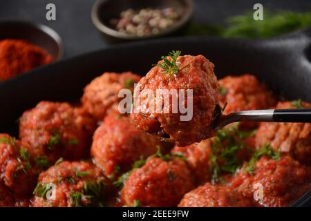 Boulettes de Poisson, gebratene Fischbälle in Tomatensauce in einer schwarzen Schale auf einem Betontisch mit Zutaten Stockfoto