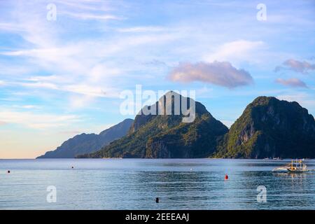Tropische Insel Silhouette in Meereslandschaft. Exotischer Ort für Urlaub. Grüner Berg im tropischen Meer. Philippinische Meereslandschaft mit Fischerboot und Tour Stockfoto