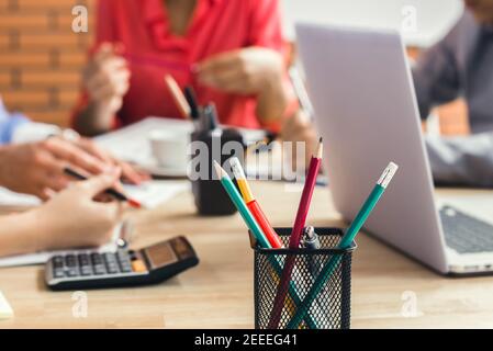 Bunte Bürobedarf mit Laptop-Computer auf dem Besprechungstisch mit Verwischen Sie Geschäftsleute im Hintergrund Stockfoto