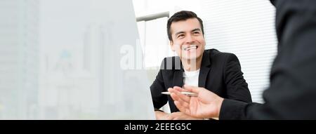 Glücklicher Geschäftsmann, der mit seinen Kollegen über die Arbeit spricht Im Büro - Panorama-Webbanner mit Kopierplatz Stockfoto