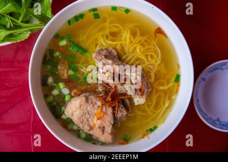 Suppe Pho mit Nudeln und Fleisch, Draufsicht Foto der vietnamesischen Küche auf rotem Tisch serviert. Pho Bo traditionelles Gericht aus Vietnam. Leckere reiche Brühe ohne Stockfoto