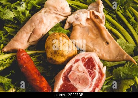 Overview Zutaten des galizischen Eintopfrezeptes während des Karnevals bestehend aus Kartoffeln, Schweinebein, lacon, geräuchertem Ohr, Chorizo ​​and Rübengemüse Stockfoto