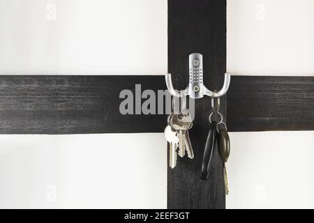 Autoschlüssel und Hausschlüssel auf einem Kleiderbügel. Neue Realität. Autoschlüssel auf einem Haken mit Platz für Text (kopieren Sie den Raum) Schlüsselanhänger Stockfoto