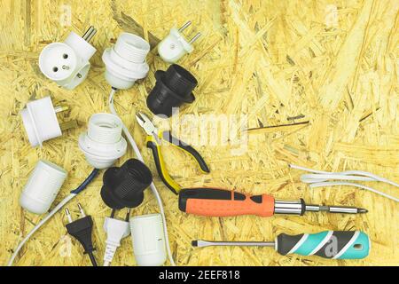 Installation der elektrischen Verdrahtung und Anschluss von Steckdosen und Steckern an Drähte. Elektrische Gegenstände und Werkzeuge werden mit leeren sp. Auf dem Tisch verteilt Stockfoto