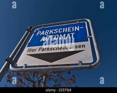 Niedrige Ansicht von blau und weiß gefärbten Zeichen mit schwarzem Pfeil, der zum Ticketautomaten eines öffentlichen Parkplatzes im Stadtzentrum führt. Stockfoto