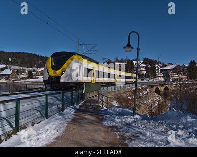 Weiß und gelb gefärbte S-Bahn der Deutschen Bahn nach Überquerung der Eisenbahnbrücke in Schluchsee, die Teil der Dreiseenbahn ist. Stockfoto