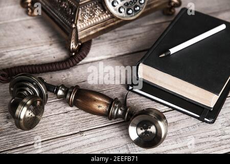 Vintage Drehtelefon und altes Telefonbuch auf dem Tisch in der Nähe Wand und Stockfoto