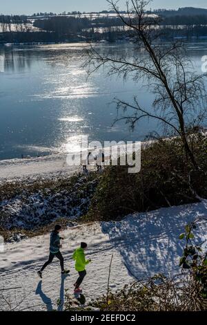 Winter im Ruhrgebiet, Baldeneysee, schneebedeckter, teilweise gefrorener See, Spaziergänger am Uferweg, Westufer, Essen, NRW, Deutschland, Stockfoto
