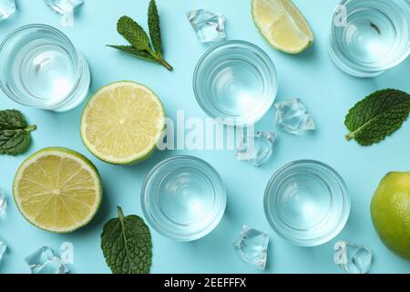 Schüsse, Limettenscheiben, Minze und Eiswürfel auf blauem Hintergrund, Draufsicht Stockfoto