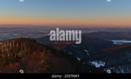 Schöne Luftaufnahme über die Ausläufer des Schwarzwaldes und Stadt Freiburg im Breisgau im Abendlicht in der Wintersaison mit Schnee. Stockfoto