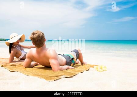 Pärchen liegen am weißen Sandstrand und entspannen sich und nehmen ein Sonnenbaden im Sommer Stockfoto