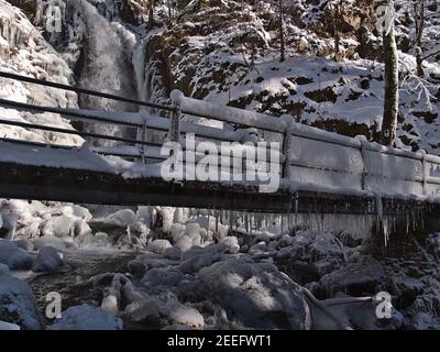 Oberer Teil der berühmten Wasserfälle Todtnauer Wasserfälle mit schneebedeckten Steg und gefrorenen Felsen in der Wintersaison an sonnigen Tagen im Schwarzwald. Stockfoto
