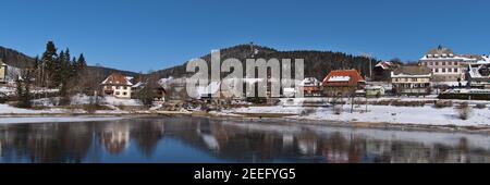 Schöner Panoramablick auf gefrorenen See und Dorf Schluchsee, Deutschland im Schwarzwald Bergkette mit schneebedeckten Häusern, Wald und Turm. Stockfoto