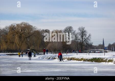 ZUTPHEN, NIEDERLANDE - 14. Feb 2021: Gefrorener Fluss Berkel mit winterkargen Bäumen und Schneelandschaft von Eisläufern genossen Stockfoto